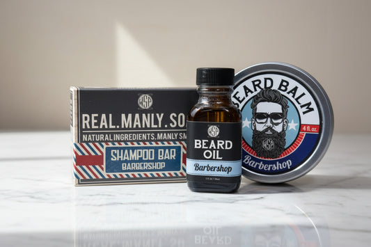 Barbershop products including a bottle of beard oil, a box of shampoo bars, and a jar of balm on a tiled surface.