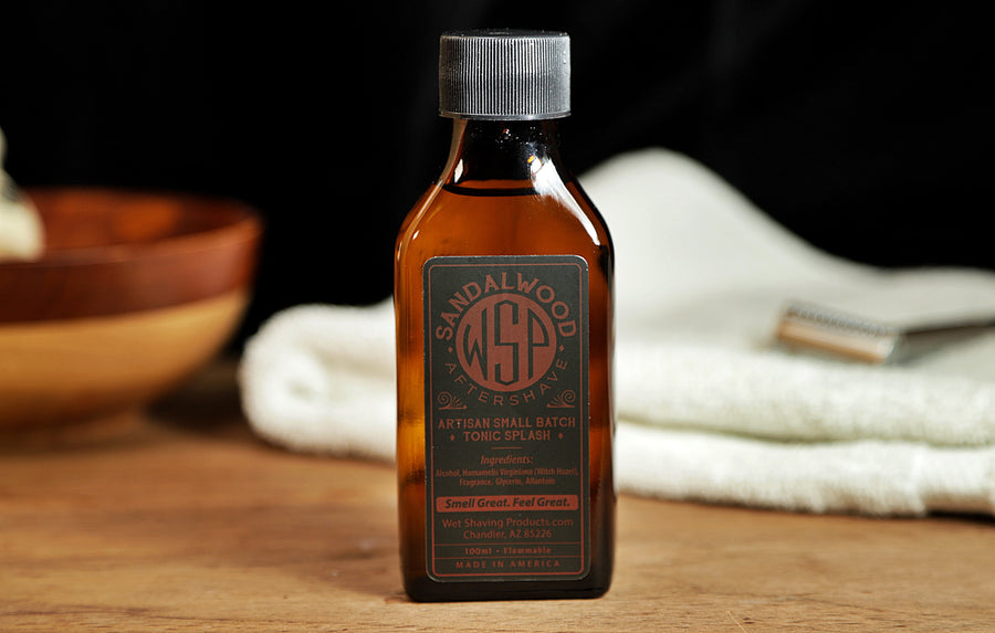 Small brown bottle of WSP Sandalwood Aftershave Tonic splash sitting on table with white towel