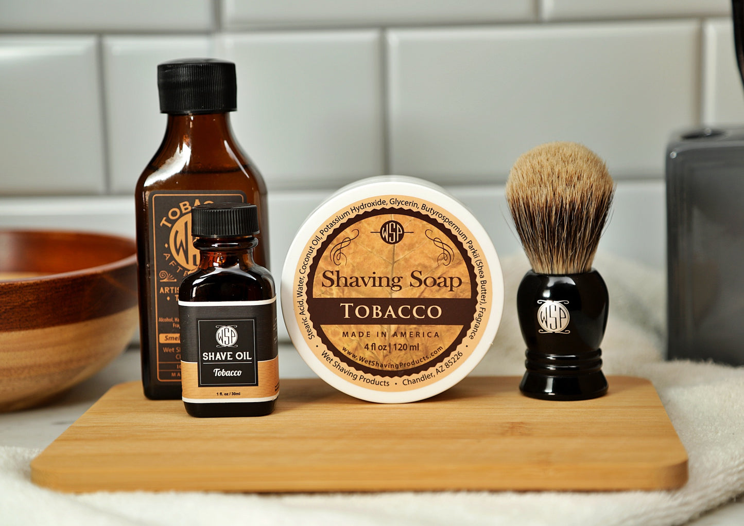 WSP Shaving Set of Tobacco shave oil, rustic shaving soap, aftershave tonic and shaving brush all sitting on wooden board with white towel