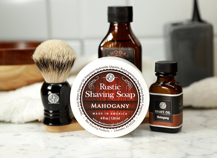 Shaving Set of Mahogany shave oil, rustic shaving soap, aftershave tonic and shaving brush all sitting on wooden board with white towel