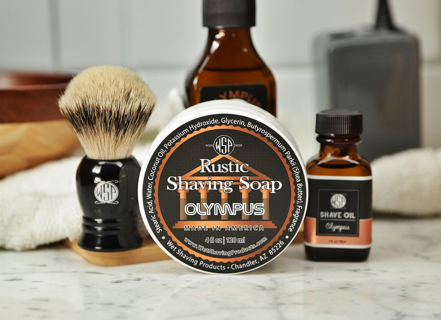 WSP Shaving Set of Olympus shave oil, rustic shaving soap, aftershave tonic and shaving brush all sitting on wooden board with white towel