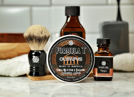 WSP Shaving Set of Olympus shave oil, rustic shaving soap, aftershave tonic and shaving brush all sitting on wooden board with white towel