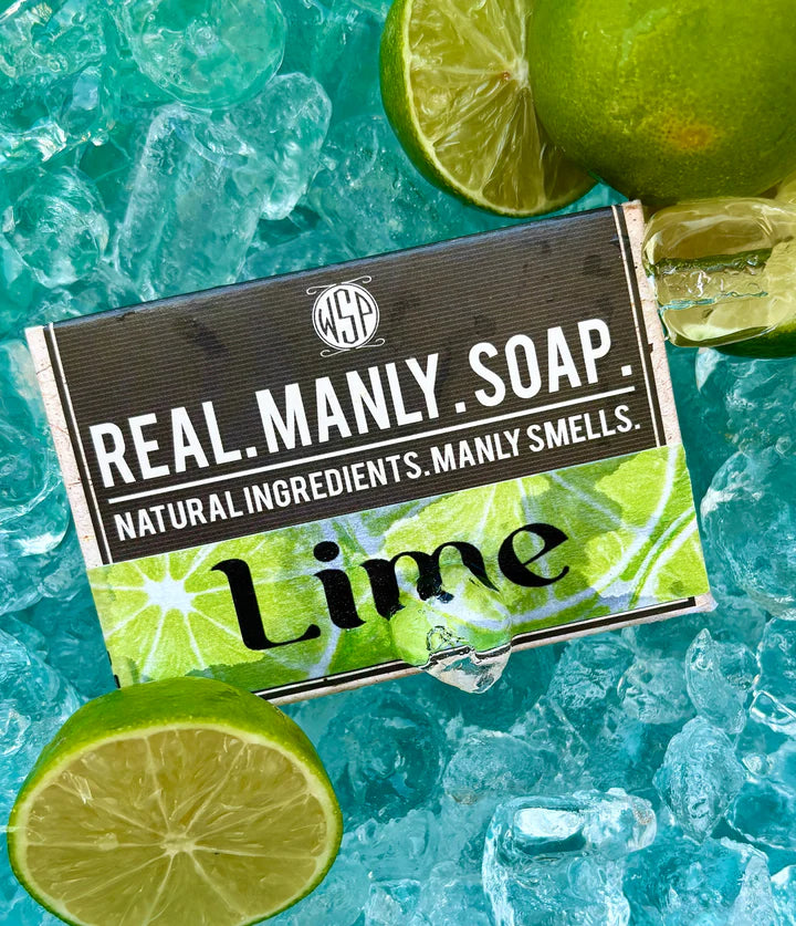 Bar of soap with 'Real Manly Soap' Lime scent packaging on a background of ice and lime slices.