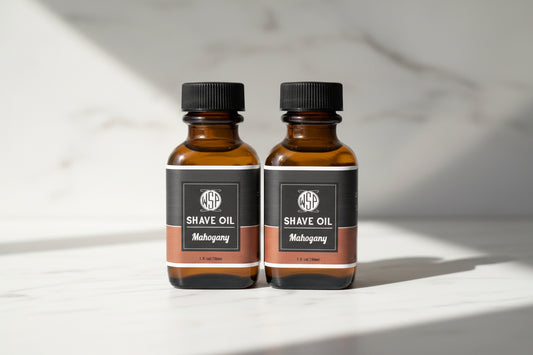 Two bottles of shave oil with black labels on a countertop.