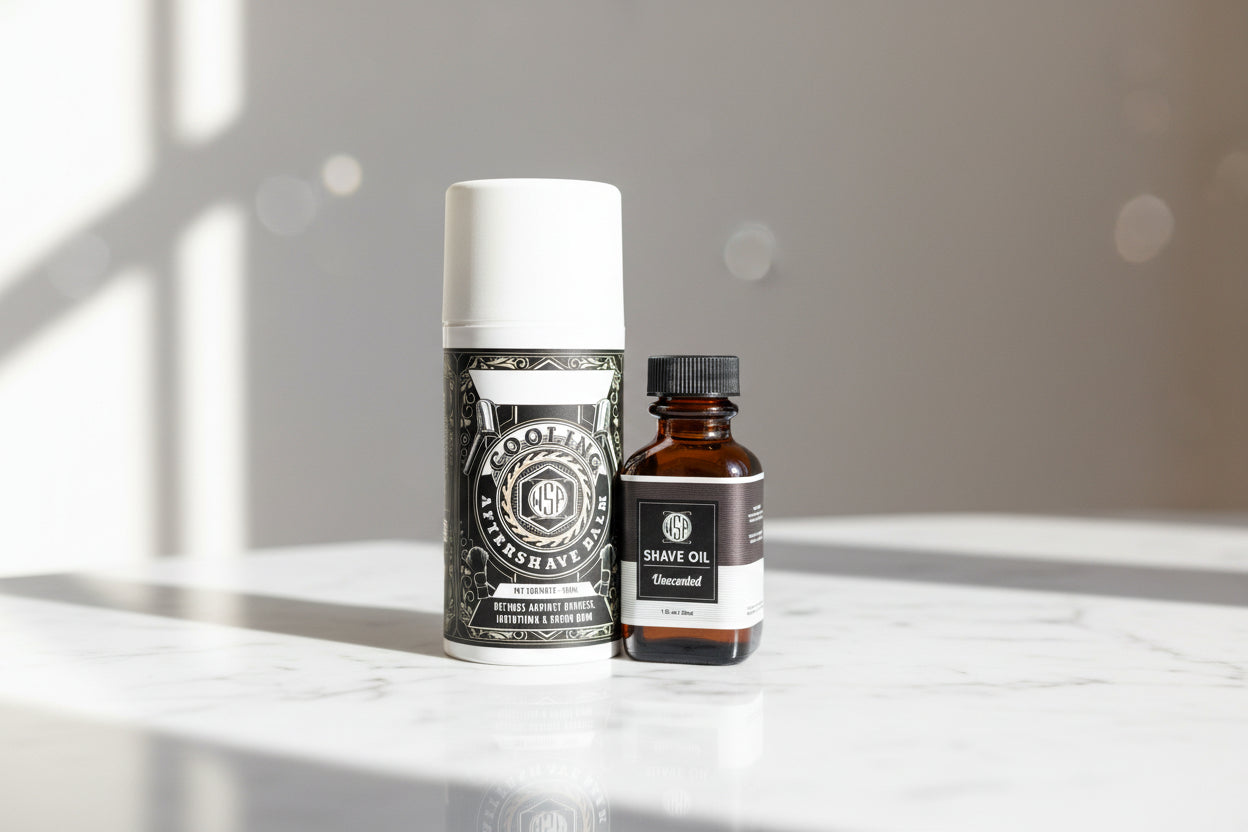 Two bottles of shave oil on a white surface with a blurred background