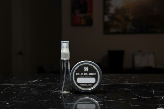 Solid cologne container and spray bottle on a dark surface with a blurred background