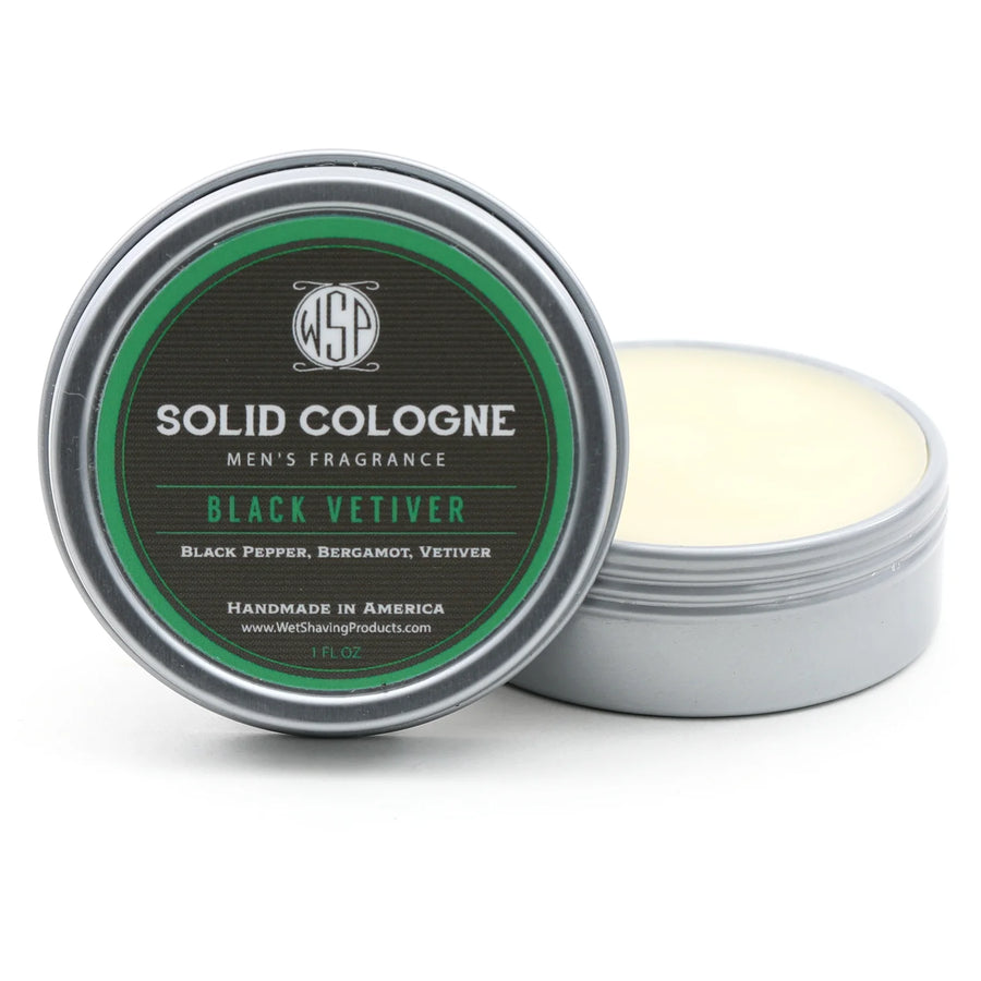 Open tin of WSP Black Vetiver Signature Solid Cologne, with the lid leaning against the fragrant solid cologne.