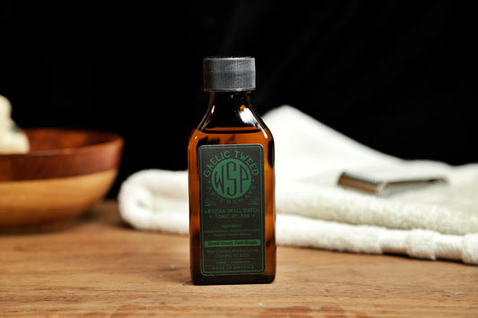 Small brown bottle of WSP Gaelic Tweed Aftershave Tonic splash sitting on table with white towel