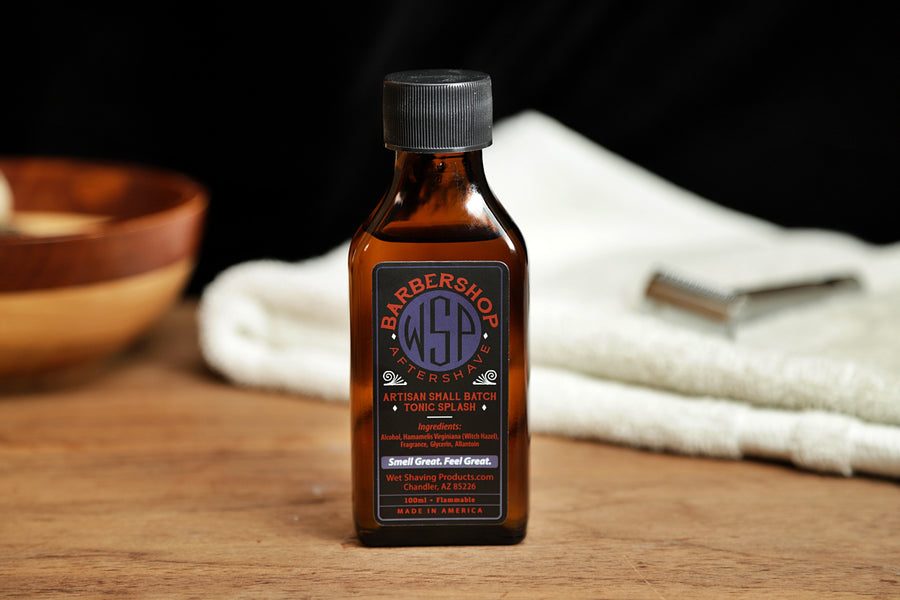 Small brown bottle of WSP Barbershop Aftershave Tonic splash sitting on table with white towel