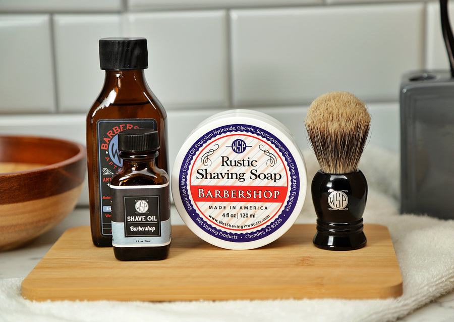 WSP Shaving Set of Barbershop shave oil, rustic shaving soap, aftershave tonic and shaving brush all sitting on wooden board with white towel