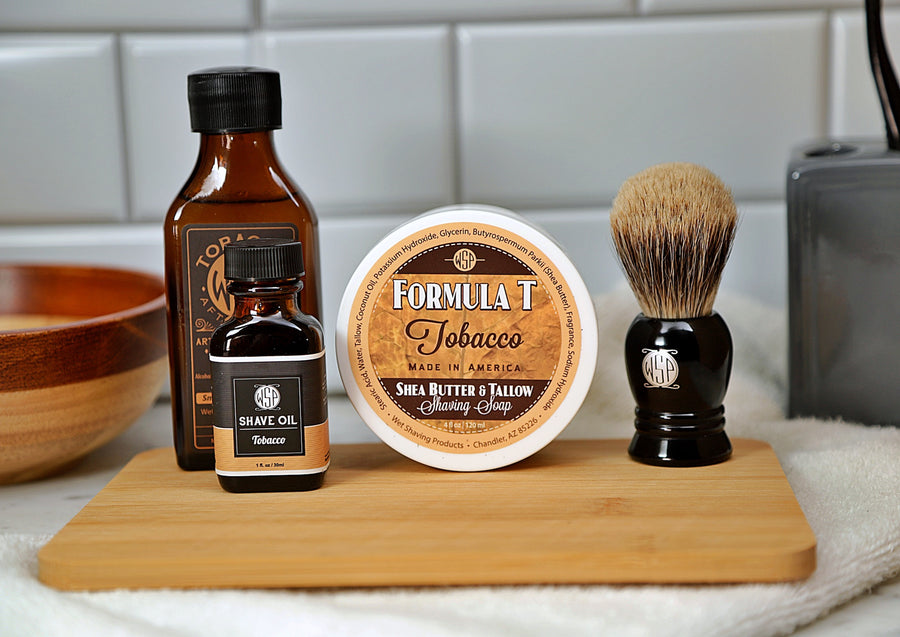 WSP Shaving Set of Tobacco shave oil, rustic shaving soap, aftershave tonic and shaving brush all sitting on wooden board with white towel