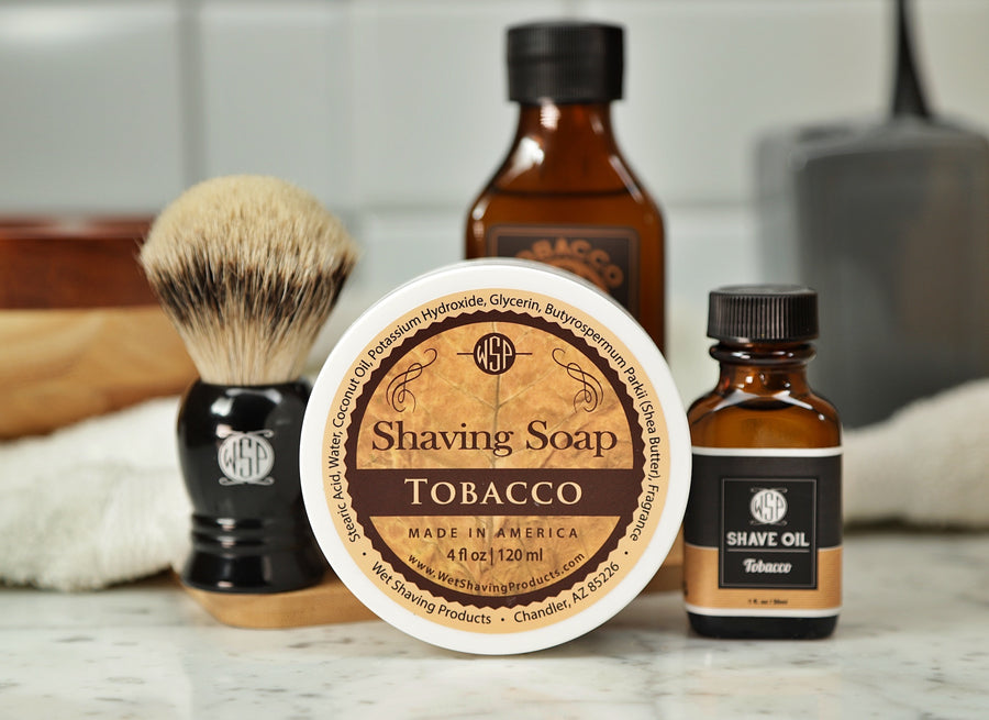 Shaving Set of Tobacco shave oil, rustic shaving soap, aftershave tonic and shaving brush all sitting on wooden board with white towel