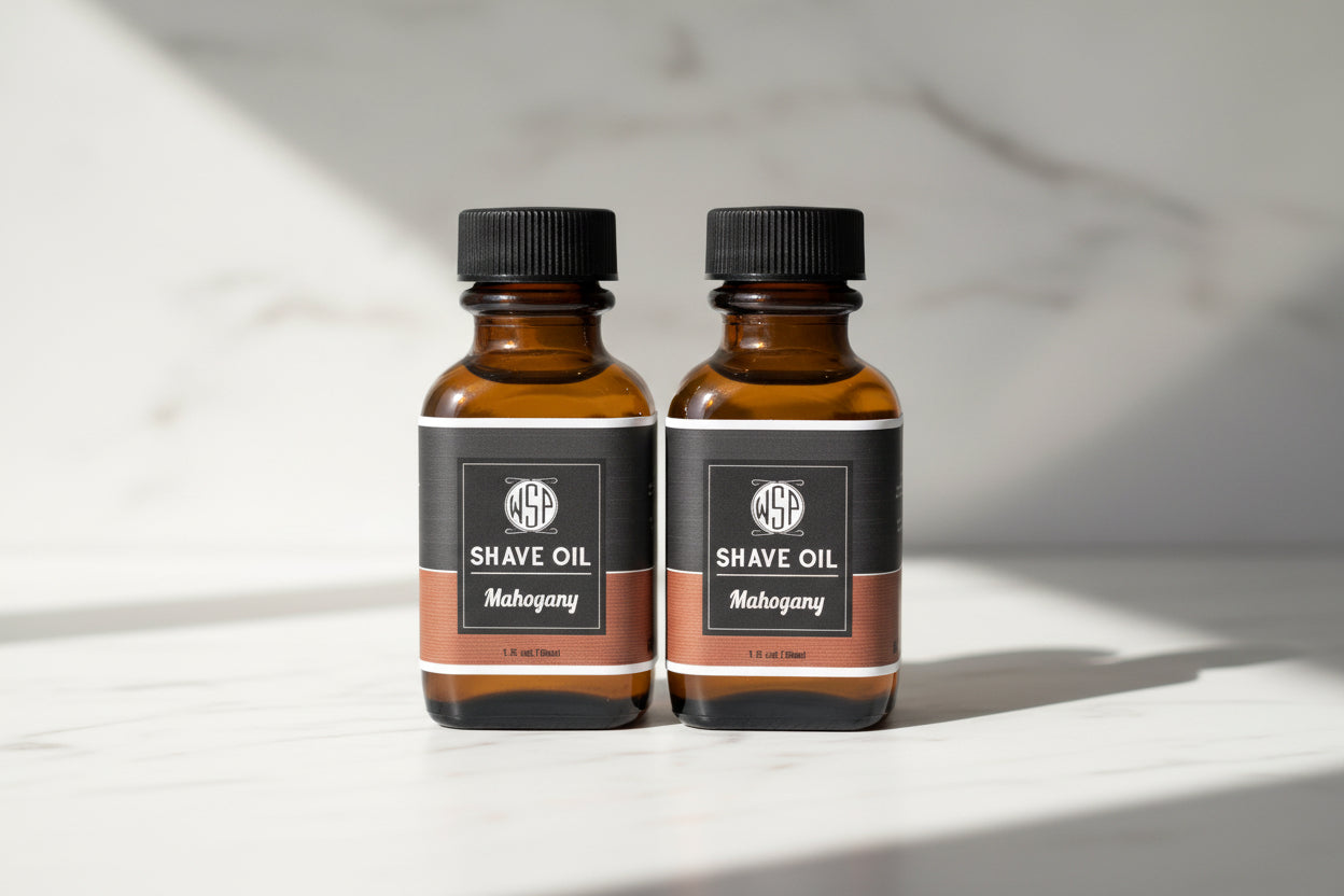 Two bottles of shave oil with black labels on a countertop.