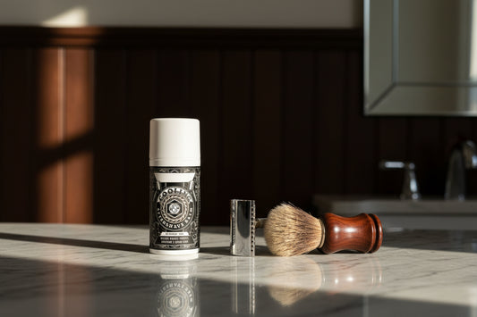Sitting on a cool grey marble bathroom countertop, next to a traditional chrome safety razor and a shaving brush, warm morning light reflecting on the surface, out of focus background of dark wood wainscoting and a mirror reflection, clean, classic barbershop atmosphere, photorealistic render.