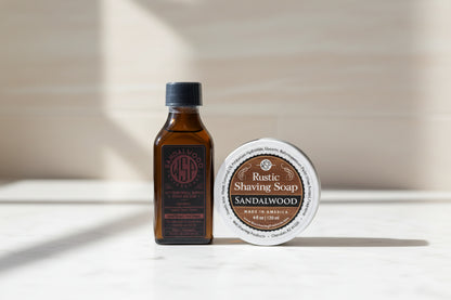 Brown bottle and white container of Rustic Shaving Soap Sandalwood on a white background