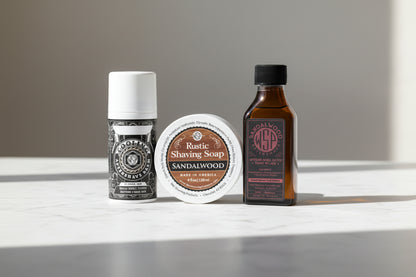 Two bottles of aftershave and a bar of sandalwood shaving soap on a textured surface.