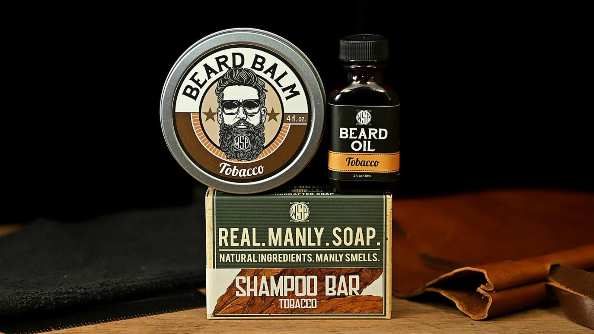 Tobacco Beard care products including balm, oil, and shampoo bar on a dark background