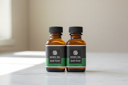 Two bottles of shave oil with black and green labels on a white surface.