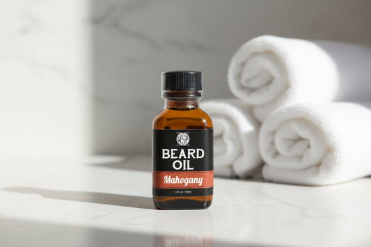 Bottle of Manegamy beard oil on a marble surface with white towels in the background
