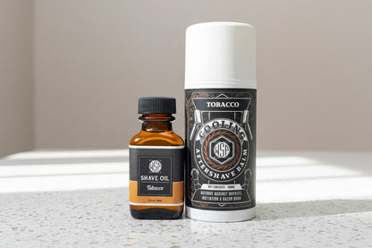 Two grooming products, a bottle of shave oil and a can of after-shave balm, on a countertop.