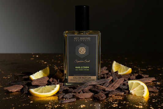 Pieces of rare, dark agarwood (oud) contrasted with bright slices of zesty citron fruit under dramatic lighting, visualizing the WSP Oud Citron Reserve fragrance.