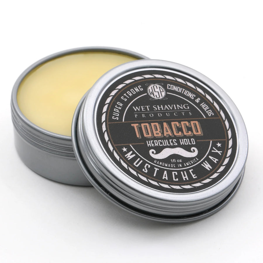 Open Hercules Hold Mustache Wax tin with 'Tobacco' scent, lid leaning against the base.